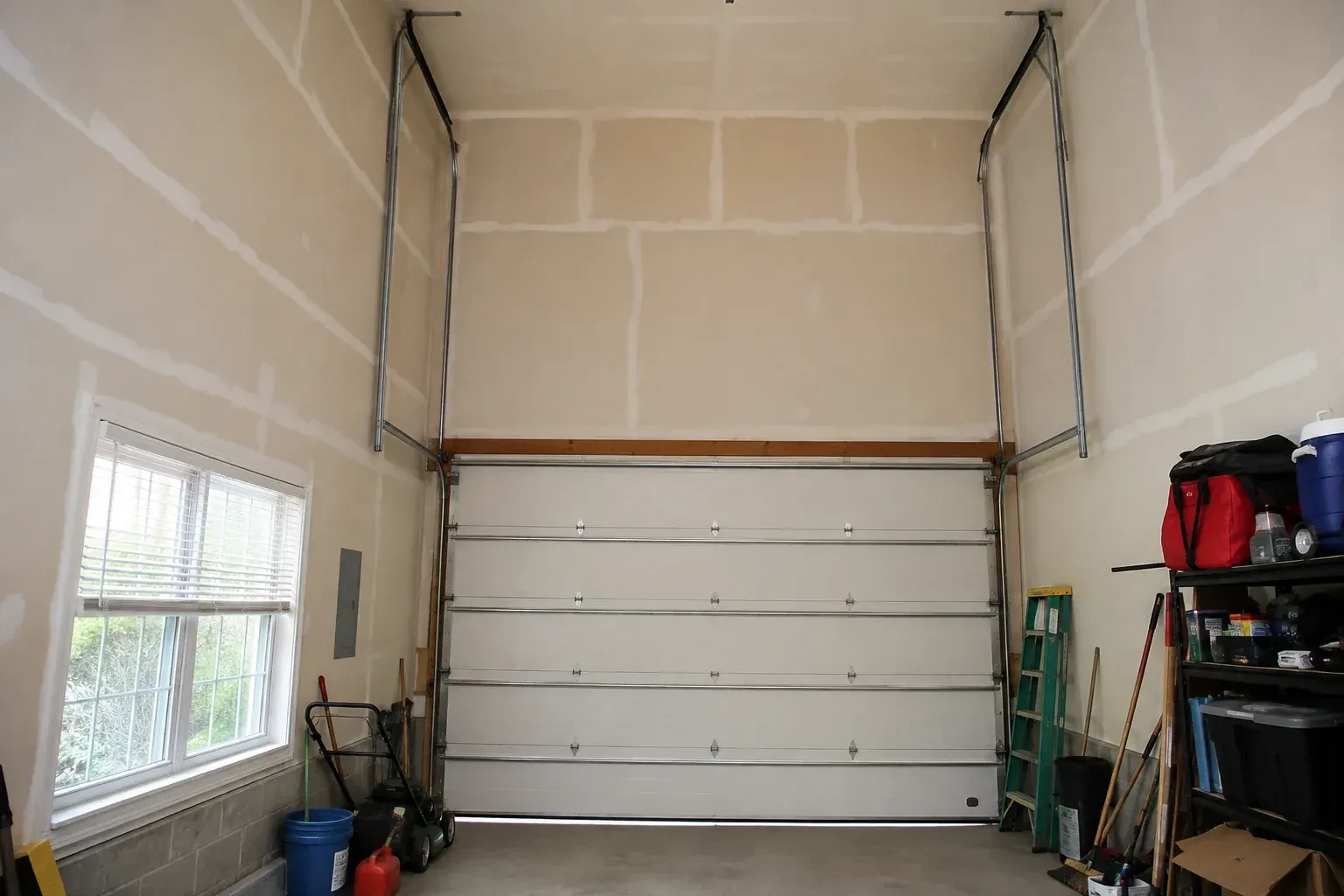 Tall garage interior with a sectional door and tracks extending into overhead space. — High-Lift Garage Door Conversion, Waterloo